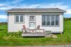 Cottage with decking and seating drenched in sunlight.